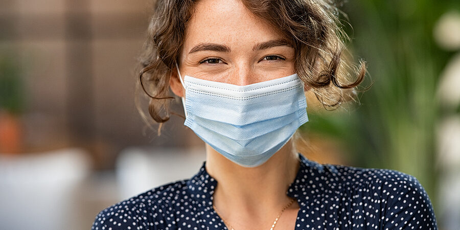 Portrait of happy young woman wearing face medical mask. Hopeful